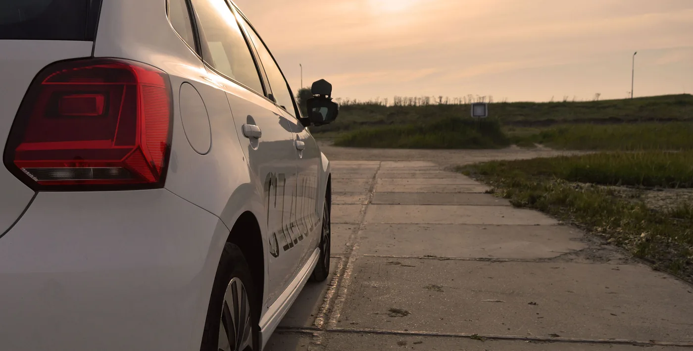 De witte lesauto aan een landelijke weg bij zonsondergang